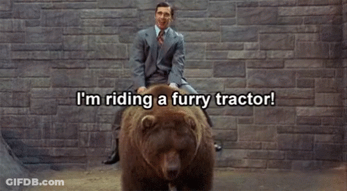 Man In Suit Riding Furry Tractor On Bear GIF