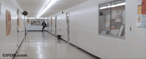Man In Suit Running Down Hallway With Posters GIF
