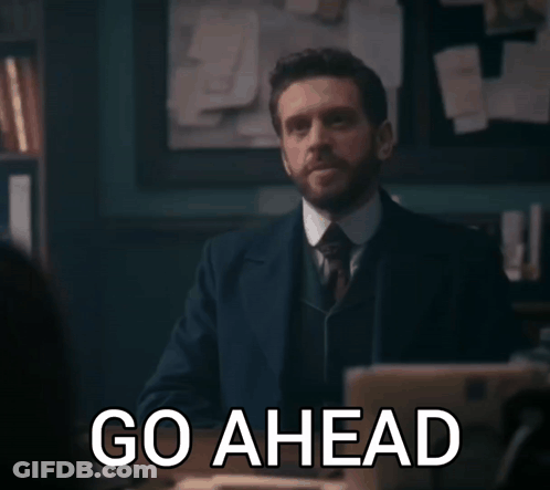 Man In Suit Saying Go Ahead In Dark Room GIF
