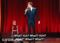Man In Suit Saying What Huh On Stage GIF