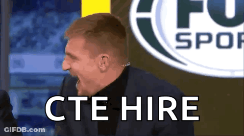 Man In Suit Says CTE Hire In Front Of Soccer Logo GIF