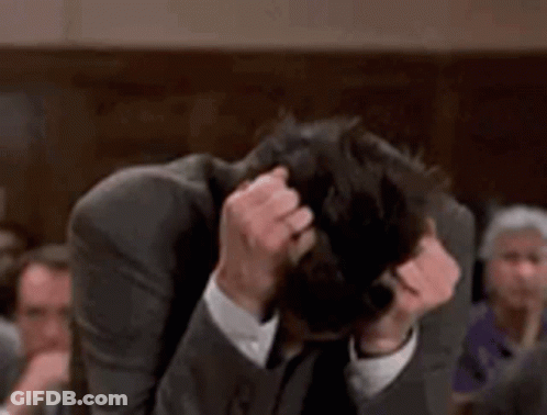 Man In Suit Scratching Head In Crowded Room GIF