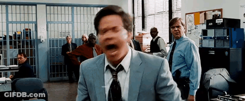 Man In Suit Screaming In Police Station With Group Behind Him GIF