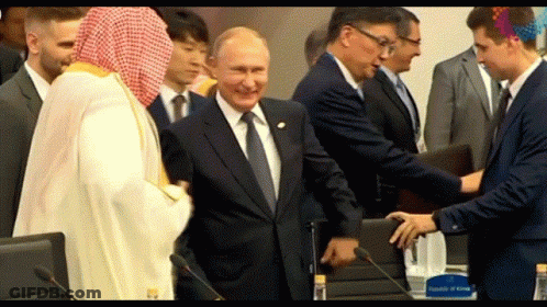Man In Suit Shaking Hands With Man In White Robe GIF