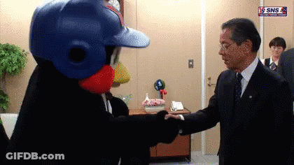 Man In Suit Shaking Hands With Mascot Wearing Baseball Helmet GIF
