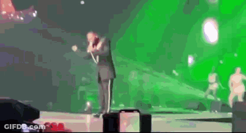 Man In Suit Singing Into Microphone On Stage GIF