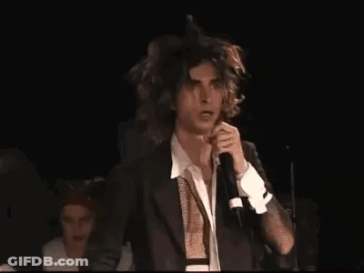 Man In Suit Singing Into Microphone On Stage GIF