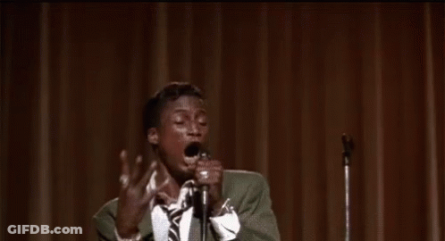 Man In Suit Singing Into Microphone On Stage GIF