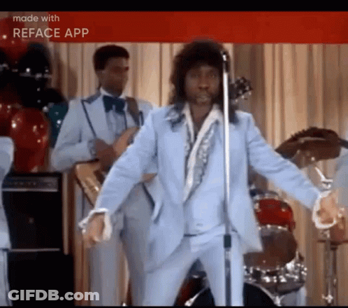 Man In Suit Singing Into Microphone While Dancing On Stage GIF