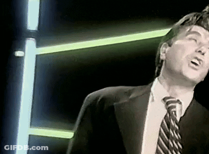 Man In Suit Singing Into Microphone With Neon Lights GIF