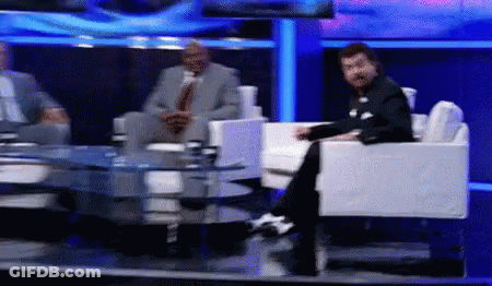 Man In Suit Sits On TV Set GIF