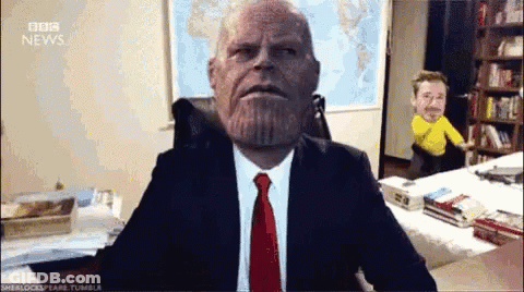 Man In Suit Sitting At Desk In Front Of BBC News Map GIF