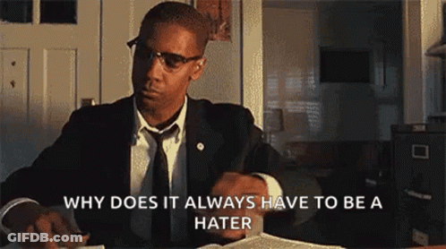 Man In Suit Sitting At Desk With Book And Glasses GIF