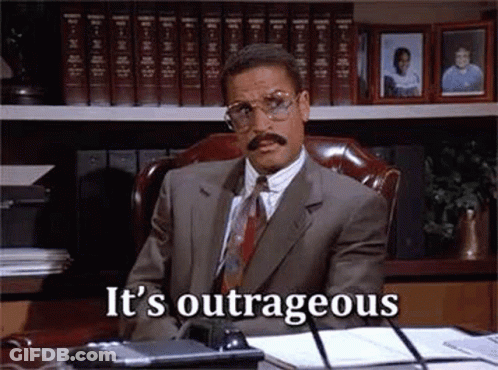 Man In Suit Sitting At Desk With Bookshelf GIF