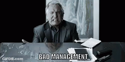 Man In Suit Sitting At Desk With Broken Glass Making Funny Face GIF