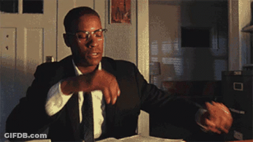 Man In Suit Sitting At Desk With Hand On Chin GIF