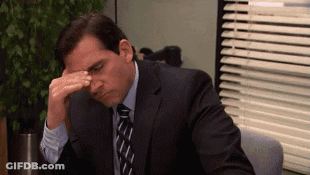 Man In Suit Sitting At Desk With Hand On Forehead GIF
