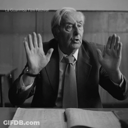 Man In Suit Sitting At Desk With Hands In Air La Guarimba Film Festival GIF