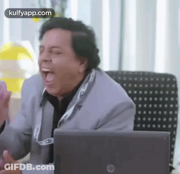 Man In Suit Sitting At Desk With Mouth Open In Front Of Laptop GIF