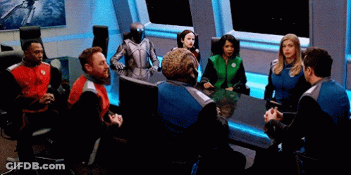 Man In Suit Sitting At Table Before Crowd GIF