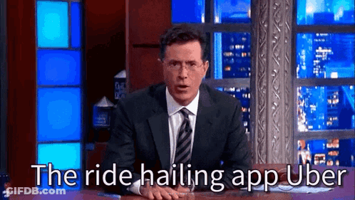 Man In Suit Sitting At Table Saying The Ride Hailing App Uber GIF