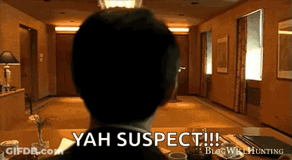 Man In Suit Sitting At Table Saying Yah Suspect GIF