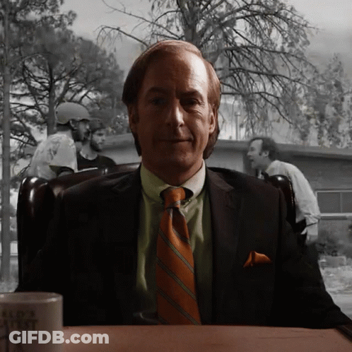 Man In Suit Sitting At Table With Bad Ass Mug GIF