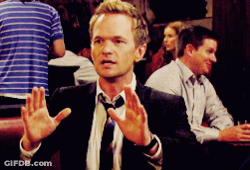 Man In Suit Sitting At Table With Hands Up GIF