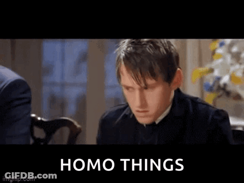 Man In Suit Sitting At Table With Homo Things Sign GIF