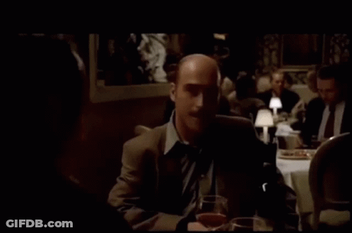 Man In Suit Sitting At Table With Wine And Beer GIF