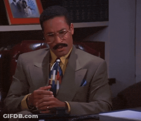 Man In Suit Sitting Before Bookshelf With Wedding Photo GIF