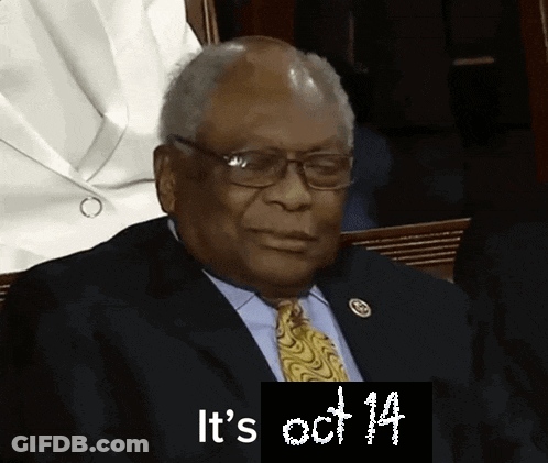 Man In Suit Sitting Before Sign Saying It's Oct 14 GIF