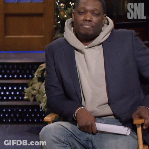 Man In Suit Sitting In Chair With SNL Logo GIF