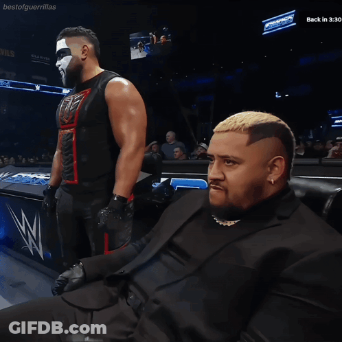 Man In Suit Sitting In Front Of Bestofguerraillas Sign GIF