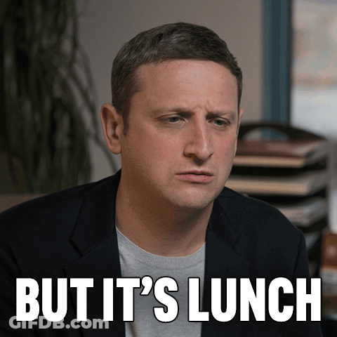 Man In Suit Sitting In Front Of But Its Lunch Sign GIF