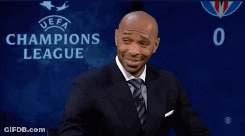 Man In Suit Sitting In Front Of Champions League Sign GIF