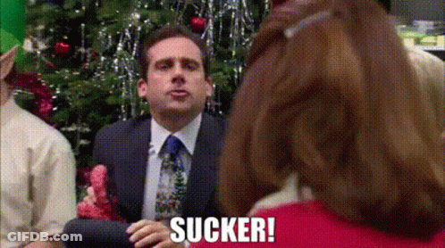 Man In Suit Sitting In Front Of Christmas Tree With Woman Behind GIF