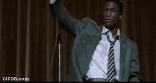 Man In Suit Sitting In Front Of Crowd GIF