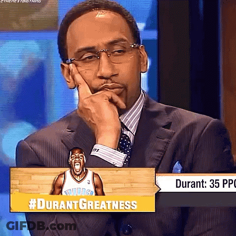 Man In Suit Sitting In Front Of #Durantgreatness Sign GIF