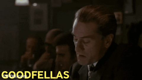 Man In Suit Sitting In Front Of Goodfellas Screen GIF