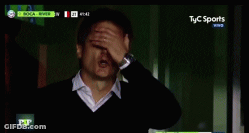 Man In Suit Sitting In Front Of Screen Saying El Nueve Vivo GIF