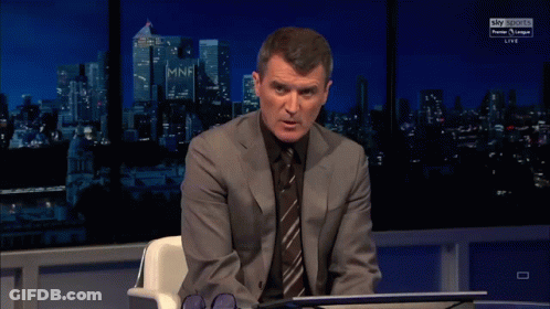 Man In Suit Sitting In Front Of Sky Sports Sign GIF