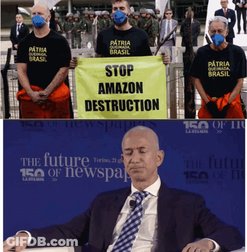 Man In Suit Sitting In Front Of Stop Amazon Destruction Sign GIF