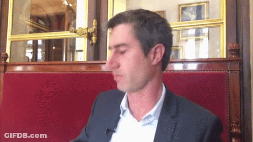 Man In Suit Sitting In Red Cushion Chair GIF