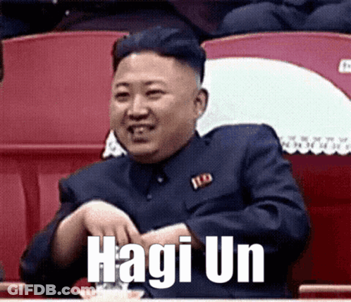 Man In Suit Sitting In Stadium With Hagi Un On Face GIF