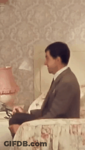 Man In Suit Sitting On Bed GIF