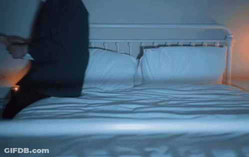 Man In Suit Sitting On Bed GIF