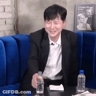 Man In Suit Sitting On Blue Couch Holding Water GIF