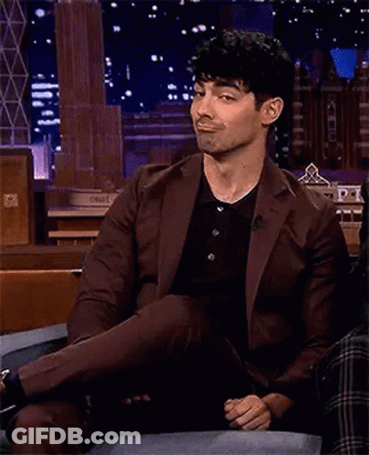 Man In Suit Sitting On Couch Crossed Leg Smiling GIF
