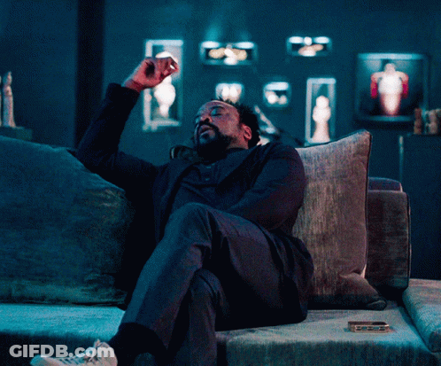 Man In Suit Sitting On Couch With Arms Outstretched GIF